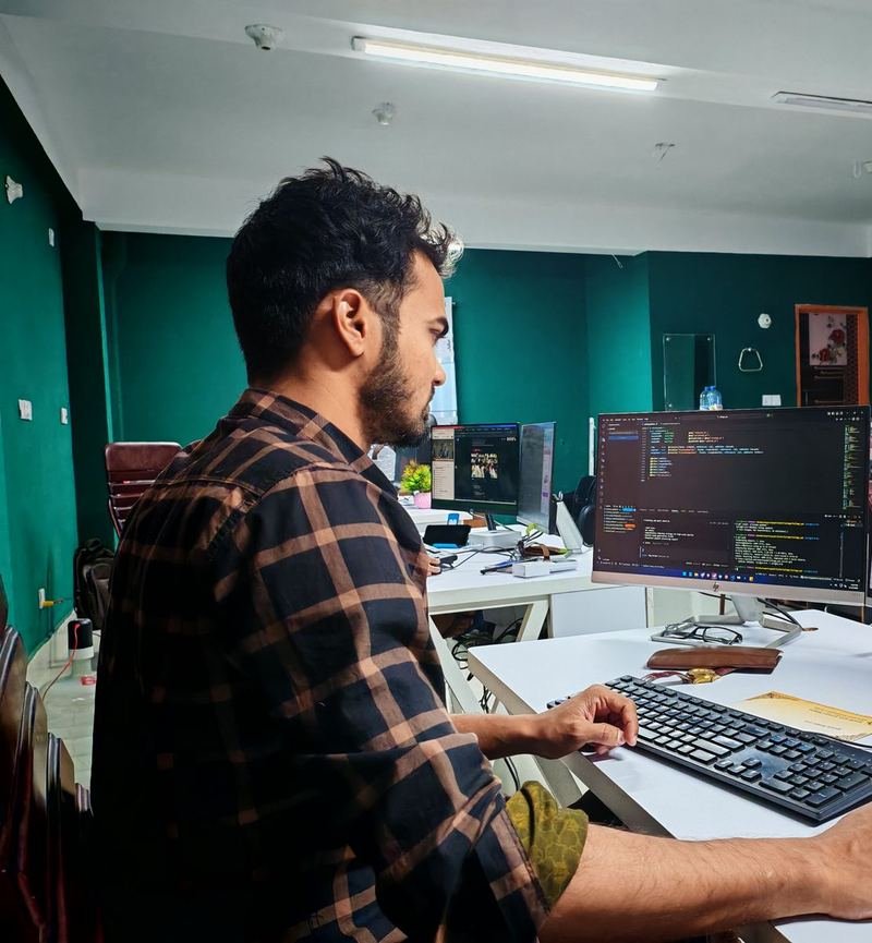 Software developer working on code across desktop monitors in an office
