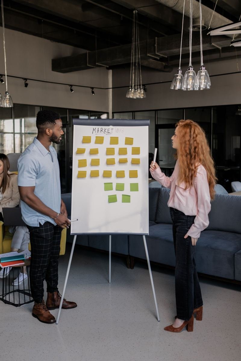 Two colleagues discussing a marketing plan on a flipchart covered in sticky notes