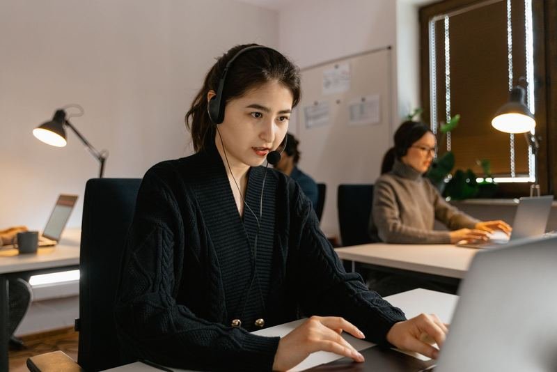 Professional wearing a headset speaking on a call while working on a laptop